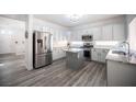 Bright kitchen featuring white cabinets, stainless steel appliances, an island, and wood-look flooring at 810 Roaring Falls Ave, Henderson, NV 89052