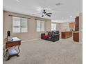Open-concept living room showcasing plush carpet, ceiling fan, and an adjoining kitchen and dining area at 8220 Redbud Vine St, North Las Vegas, NV 89085