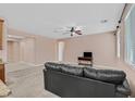 A living room featuring neutral colors, plush carpet, ceiling fan, and filled with natural light from the large window at 8220 Redbud Vine St, North Las Vegas, NV 89085