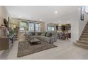Comfortable living room featuring tile floors, a plush sectional sofa, and natural light streaming through large windows at 8992 Sparkling River Ct, Las Vegas, NV 89178