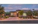 Beautiful home exterior featuring professional landscaping, brick driveway and tasteful outdoor lighting at 9928 Regency Square Ave, Las Vegas, NV 89148