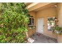 Cozy front porch area with a white door, lush greenery, and a decorative outdoor lantern at 9948 Bundella Dr, Las Vegas, NV 89134