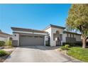 Single-story home featuring a two-car garage and a beautifully landscaped front yard with an arched entryway at 2964 Via Della Amore, Henderson, NV 89052