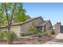 Exterior view of the home featuring desert landscaping, a brick gate, and well-maintained grounds at 423 Red Canvas Pl, Las Vegas, NV 89144