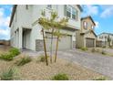 Two-story home with tan painted exterior, stone accents, a two-car garage, and a brick driveway at 5016 Kaslo Ave, Las Vegas, NV 89139