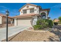 View of a charming two-story home with an attached two-car garage, desert landscaping, and a beautiful lawn at 5044 Signal Dr, Las Vegas, NV 89130
