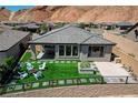 A backyard featuring artificial turf, white lounge chairs, and black metal fence at 54 Mirage View Dr, Henderson, NV 89011