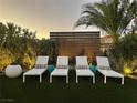 A lovely backyard with four white lounge chairs, decorative side tables and mature landscaping at 6316 Bluejay Way, Las Vegas, NV 89146