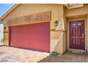 Close up of a red garage door and front door, complimented by upgraded brick driveway and desert landscaping at 7902 Jessamy St, North Las Vegas, NV 89084