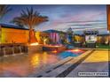Backyard view of pool, spa, fire feature and tv at dusk at 9091 Becket Ranch Ct, Las Vegas, NV 89113