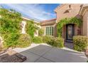 Inviting front entrance with mature landscaping, a stone walkway, and a decorative glass door at 2489 Black River Falls Dr, Henderson, NV 89044