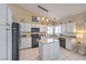Bright kitchen featuring white cabinets, a center island, black appliances, and tile floors at 8942 Galena Crossing St, Las Vegas, NV 89123