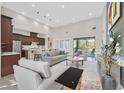 Open-concept living room and kitchen with high ceilings, modern lighting, and large windows at 10150 Emerald Sunset Ct, Las Vegas, NV 89148