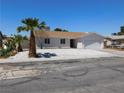 Single-story home with desert landscaping, including mature palm trees and a well-manicured yard at 1075 Greymouth St, Las Vegas, NV 89110