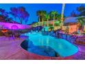 Beautiful backyard pool with rock waterfall feature, tropical plants, and ambient lighting at 112 Kava Kava St, Henderson, NV 89015