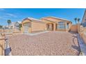 Tan house with low-maintenance desert landscaping, complemented by a gated fence and tiled roof under a blue sky at 1437 Daybreak Dr, Las Vegas, NV 89108