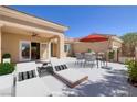 This patio is complete with lounge chairs, an outdoor table and seating under an umbrella, great for entertaining at 2219 Sawtooth Mountain Dr, Henderson, NV 89044