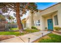 Well-maintained front yard featuring a walkway leading to a turquoise front door, lush landscaping, and mature trees at 2251 Van Gogh Dr, Henderson, NV 89074