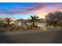 Inviting single-story home with a two-car garage, desert landscaping, and mature palm trees at sunset at 2862 Sapphire Desert Dr, Henderson, NV 89052