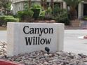 Canyon Willow stone sign surrounded by landscaped rocks and lush greenery in a charming community entrance at 5241 Caspian Springs Dr # 103, Las Vegas, NV 89120