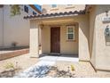 Covered front porch with a brown front door, desert landscaping, and exterior lighting at 5638 Jelsma Ave, Las Vegas, NV 89141