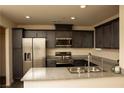 Modern kitchen featuring stainless steel appliances, granite counters, and dark wood cabinets at 6824 Satin Silver Ct, North Las Vegas, NV 89086
