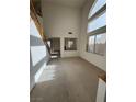 Bright living room features high ceilings, large windows, and a staircase with wood railing at 9641 Windborne Ave, Las Vegas, NV 89147