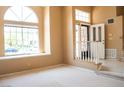 Inviting living room featuring large windows, a decorative door, and neutral carpet at 9704 Falling Star Ave, Las Vegas, NV 89117