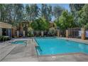 A tranquil community pool and jacuzzi surrounded by lush greenery and a secure fence at 2141 Hussium Hills St # 102, Las Vegas, NV 89108
