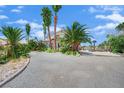Gravel driveway leads to the two-story home, accented by palm trees and mature landscape at 5890 W Patrick Ln, Las Vegas, NV 89118