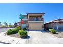 Two-story home featuring a balcony, tan stucco, stone accents, and a well-kept lawn at 7609 Rory Ct, Las Vegas, NV 89129
