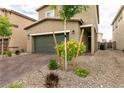 View of the front of a well-manicured home with a two-car garage, young trees and easy to maintain gravel landscaping at 7721 Sheliak St, North Las Vegas, NV 89084