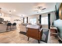 Open-concept living room featuring tile flooring, a ceiling fan, modern decor, and abundant natural light from the windows at 7721 Sheliak St, North Las Vegas, NV 89084