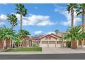 Charming home featuring a well-maintained lawn, desert landscaping, palm trees, and a three-car garage at 1324 European Dr, Henderson, NV 89052