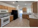 Spacious kitchen with tile floors, wood cabinets, marble countertops and white and black appliances at 3029 Frigate Way, North Las Vegas, NV 89084