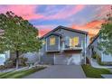 Charming two-story home with a balcony, a well-maintained lawn, and mature trees against a colorful sky at 3080 Yankee Clipper Dr, Las Vegas, NV 89117