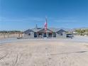 Single story home with a covered front porch, desert landscaping, and an American flag at 3880 Rudek St, Pahrump, NV 89061