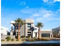 Modern home exterior with sleek lines, palm trees, and a well-maintained front yard under a bright blue sky at 4024 Desert Trace Ct, Las Vegas, NV 89129