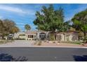 This home offers mature landscaping and a circular driveway, complete with a mature shade tree, creating curb appeal at 4594 Blue Mesa Way, Las Vegas, NV 89129