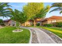 Charming home with green lawn, trees, decorative stone pathway, and accent lighting at 8275 W Craig Rd, Las Vegas, NV 89129