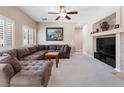 Cozy living room features a large sectional sofa, fireplace, neutral carpet, and plantation shutters at 11219 Castellane Dr, Las Vegas, NV 89141