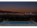Inviting pool area with stunning views of the city skyline at twilight; relax in style at 25 Rockstream Dr, Henderson, NV 89012