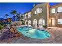 Stunning backyard with a sparkling pool, spa, rock waterfall feature, and outdoor seating area at 2571 Red Springs Dr, Las Vegas, NV 89135