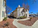 This exterior features mature landscaping, a walkway, and a view of the condo community set against a clear blue sky at 3038 Tarpon Dr # 203, Las Vegas, NV 89120