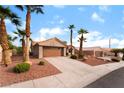 Welcoming single-story home with a two-car garage surrounded by mature palm trees and desert landscaping at 3157 Faiss Dr, Las Vegas, NV 89134