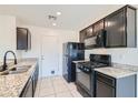 Galley kitchen featuring black appliances, granite countertops, and white tile flooring at 4539 Cotton Quail Ave, Las Vegas, NV 89115