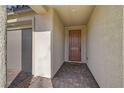 Inviting covered entryway with brick-paved flooring leading to a wood front door and a two-car garage at 6544 Sandero Springs St, Las Vegas, NV 89166