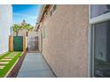 Side yard with newly laid artificial grass and a walkway leading to a white-gated entrance at 7572 Hope Valley St, Las Vegas, NV 89139