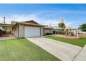View of the driveway leading to the attached garage showcasing the home's exterior and manicured front lawn at 4428 Ash Ave, Las Vegas, NV 89110