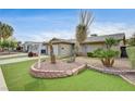 Landscaped front yard featuring desert landscaping, a brick planter and green turf, adding to the home's curb appeal at 4428 Ash Ave, Las Vegas, NV 89110